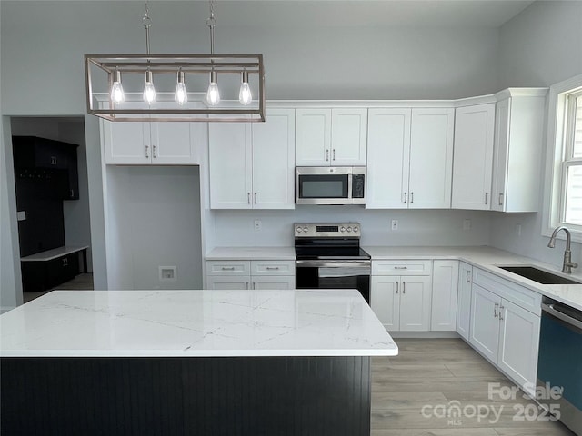 kitchen featuring decorative light fixtures, light stone counters, sink, and appliances with stainless steel finishes