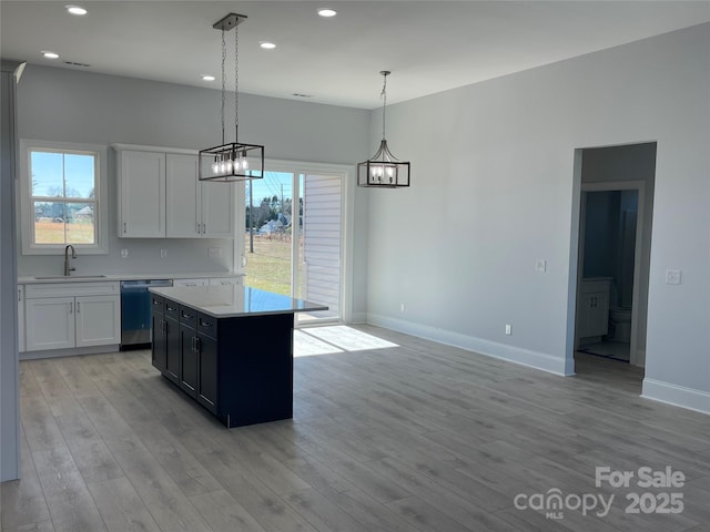 kitchen with a kitchen island, sink, dishwasher, white cabinetry, and hanging light fixtures