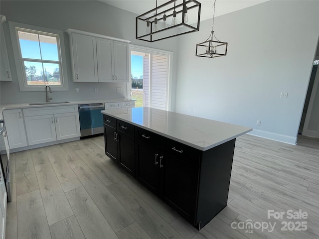 kitchen featuring dishwasher, a center island, sink, decorative light fixtures, and white cabinets