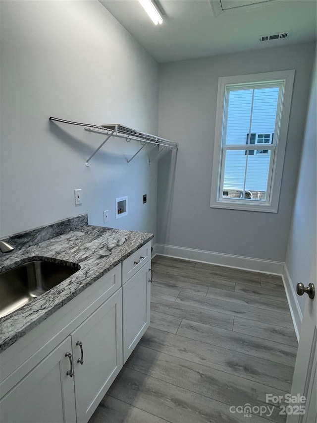 laundry area with cabinets, sink, light hardwood / wood-style flooring, washer hookup, and hookup for an electric dryer