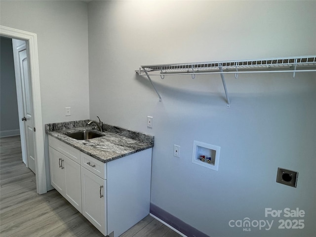 clothes washing area featuring cabinets, sink, washer hookup, hookup for an electric dryer, and light hardwood / wood-style floors