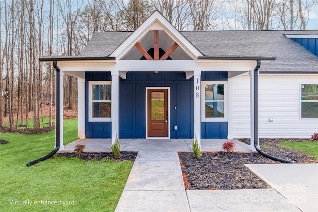 view of front of home with a front lawn, board and batten siding, and roof with shingles