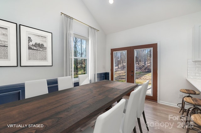 dining space with light wood-style floors, lofted ceiling, french doors, and recessed lighting