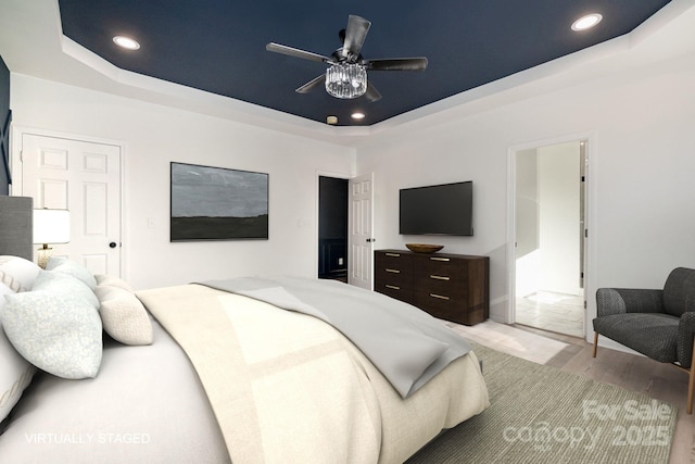 bedroom featuring a tray ceiling, wood finished floors, and recessed lighting