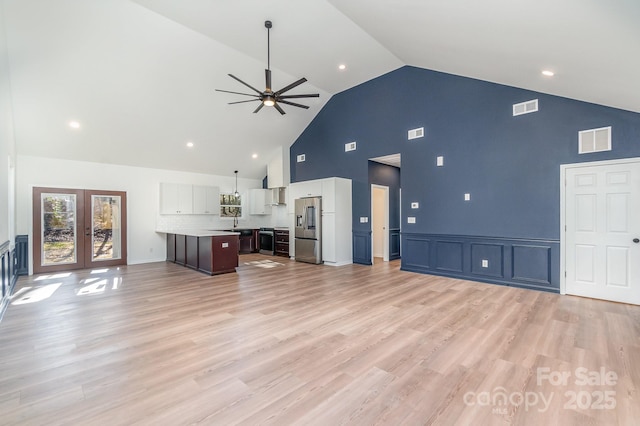 unfurnished living room with light wood-type flooring, visible vents, a ceiling fan, and french doors