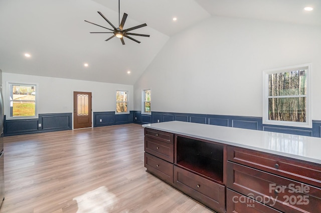 kitchen featuring light wood finished floors, recessed lighting, light countertops, wainscoting, and high vaulted ceiling