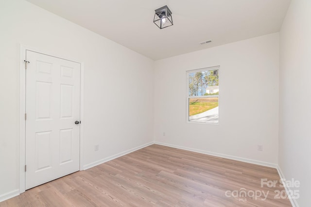 empty room featuring visible vents, light wood-style flooring, and baseboards