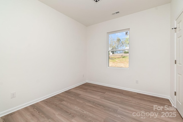 empty room with visible vents, baseboards, and wood finished floors