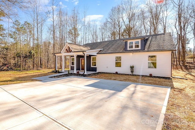 view of front of house featuring driveway, covered porch, and roof with shingles