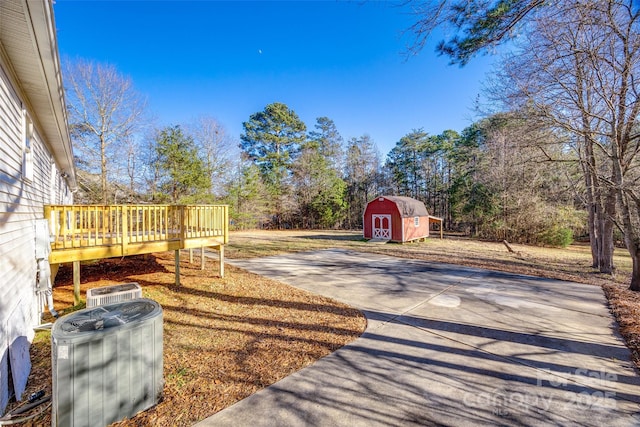 view of yard with cooling unit, a storage shed, and a wooden deck