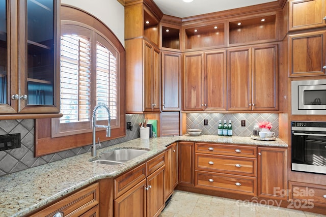 kitchen featuring decorative backsplash, sink, light stone countertops, and stainless steel appliances