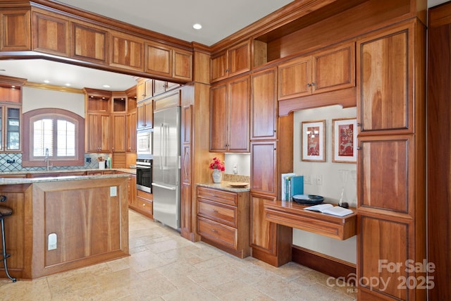 kitchen with tasteful backsplash, built in appliances, light stone counters, and crown molding