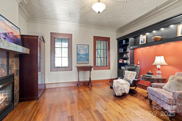 living area featuring hardwood / wood-style floors, crown molding, and a fireplace