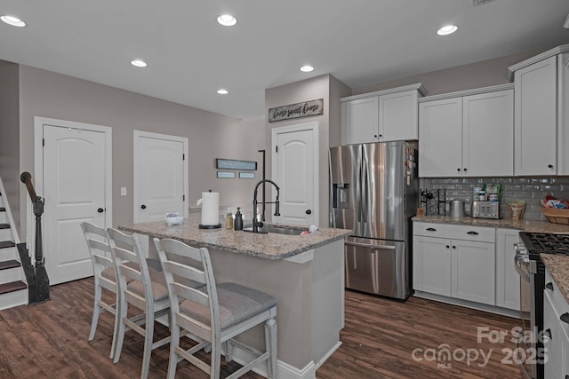 kitchen with appliances with stainless steel finishes, white cabinetry, a kitchen island with sink, and sink