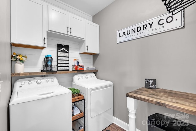 washroom featuring washing machine and dryer, wood-type flooring, and cabinets