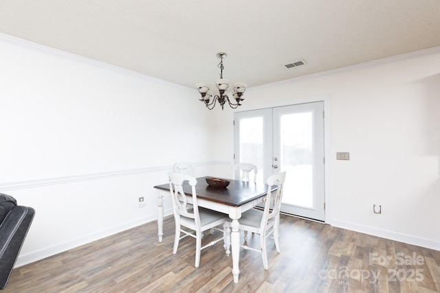 dining space with french doors, an inviting chandelier, ornamental molding, and hardwood / wood-style floors