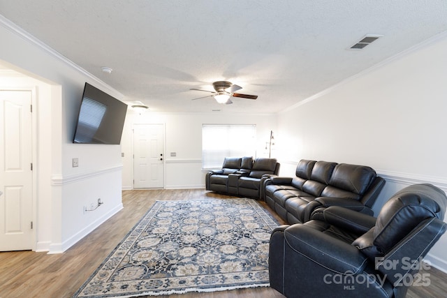 living room featuring a textured ceiling, hardwood / wood-style flooring, ceiling fan, and ornamental molding