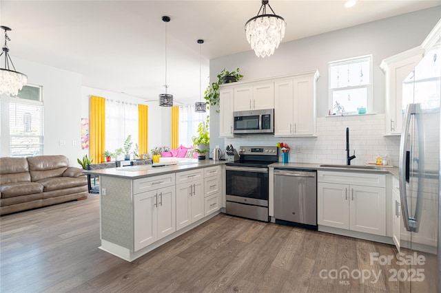 kitchen featuring hanging light fixtures, a peninsula, stainless steel appliances, and a sink