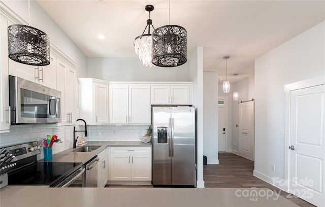 kitchen featuring white cabinetry, appliances with stainless steel finishes, pendant lighting, and a sink