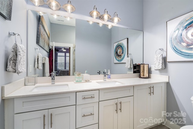 bathroom featuring ceiling fan, double vanity, a sink, and toilet