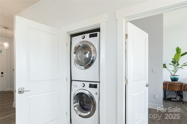 clothes washing area featuring laundry area, baseboards, dark wood finished floors, and stacked washer / drying machine