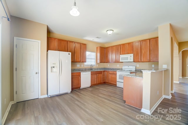 kitchen with sink, light stone counters, decorative light fixtures, white appliances, and light wood-type flooring