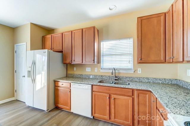 kitchen with white appliances, light stone counters, light hardwood / wood-style flooring, and sink