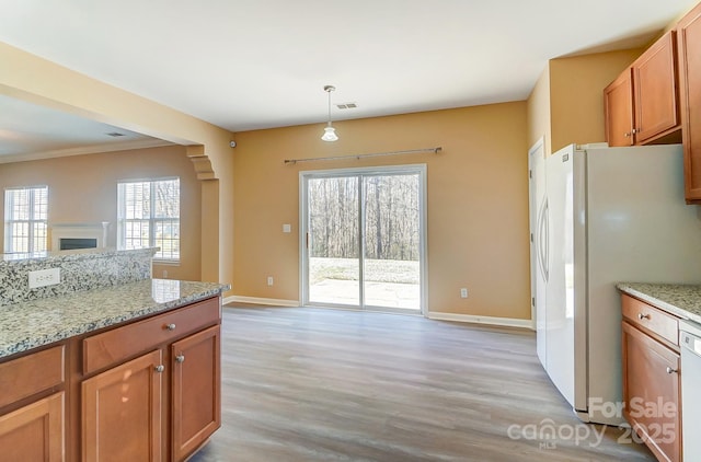 kitchen featuring light wood-type flooring, pendant lighting, white appliances, and light stone counters