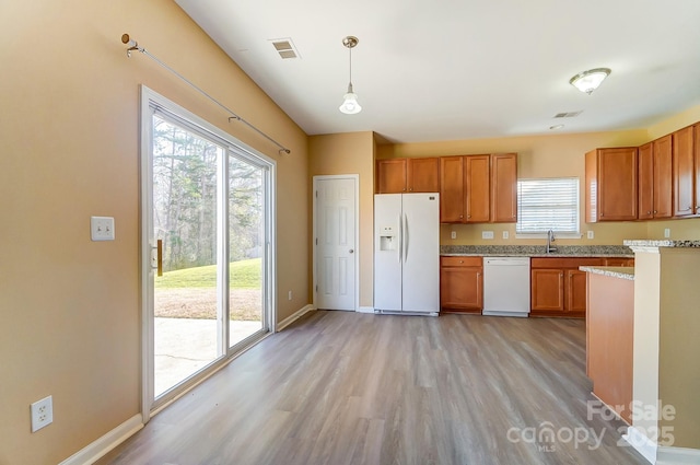 kitchen featuring light hardwood / wood-style flooring, decorative light fixtures, white appliances, and sink