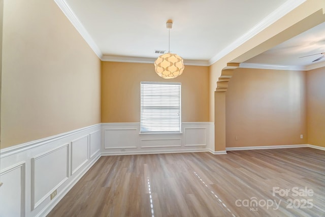 spare room featuring crown molding and light hardwood / wood-style floors