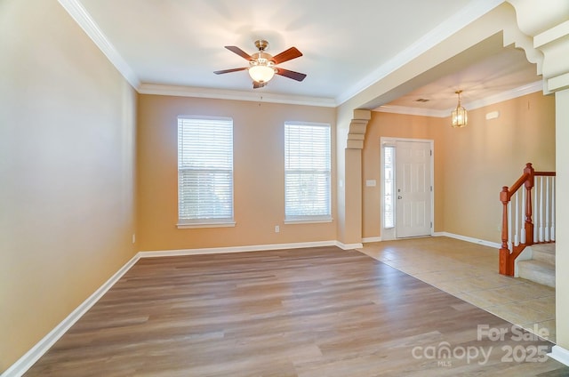 foyer entrance featuring hardwood / wood-style flooring, ceiling fan with notable chandelier, and ornamental molding