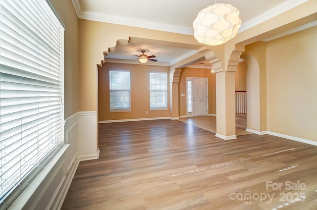 unfurnished living room with hardwood / wood-style floors, ornate columns, ceiling fan, and crown molding