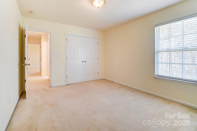 unfurnished bedroom featuring a closet and light colored carpet