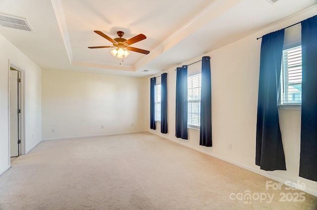 unfurnished room with ceiling fan, a raised ceiling, and light carpet