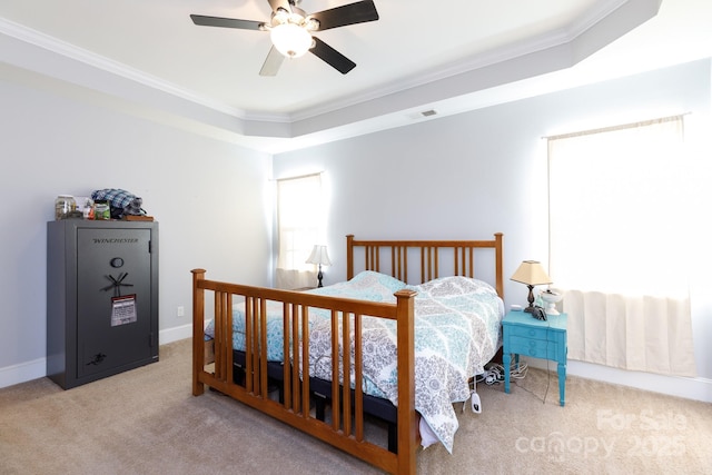 carpeted bedroom with a tray ceiling, ceiling fan, and crown molding