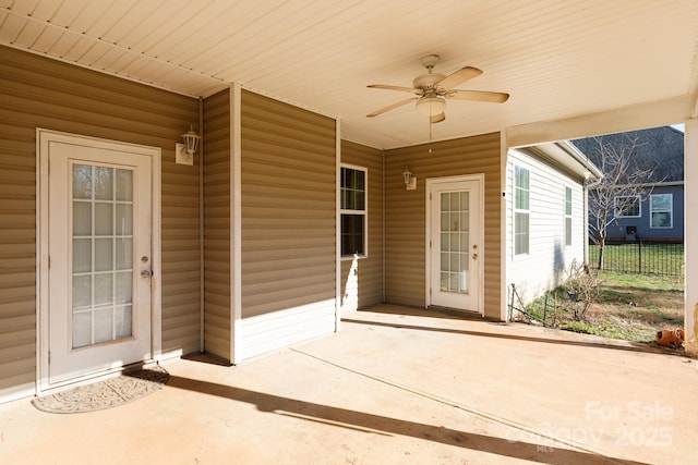 view of exterior entry with ceiling fan and a patio