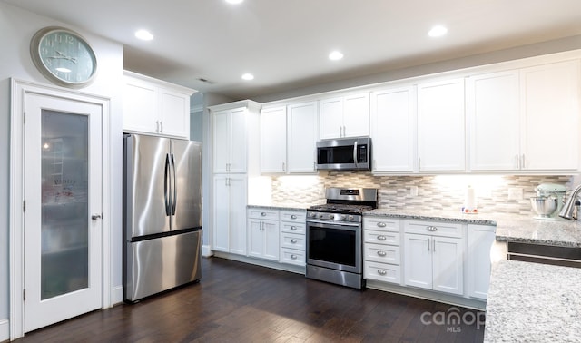 kitchen with light stone countertops, white cabinetry, tasteful backsplash, and stainless steel appliances