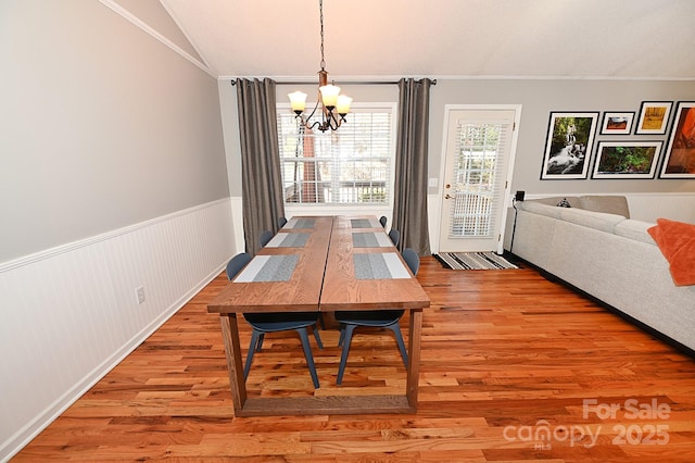 dining room featuring vaulted ceiling, hardwood / wood-style floors, and a notable chandelier