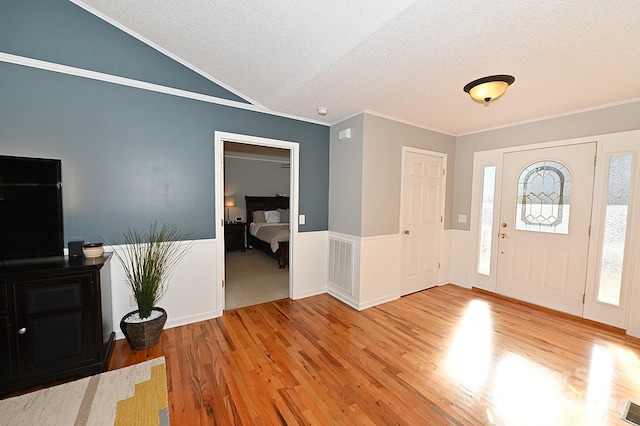 entrance foyer with hardwood / wood-style flooring, lofted ceiling, crown molding, and a textured ceiling