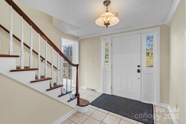 entrance foyer featuring light tile patterned flooring, ornamental molding, and a textured ceiling