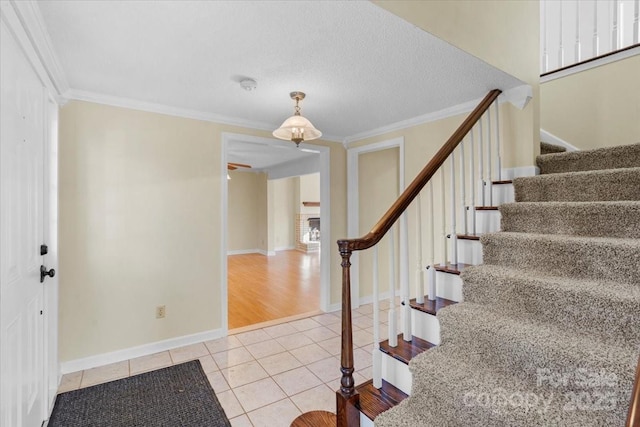 tiled entrance foyer featuring a textured ceiling and crown molding