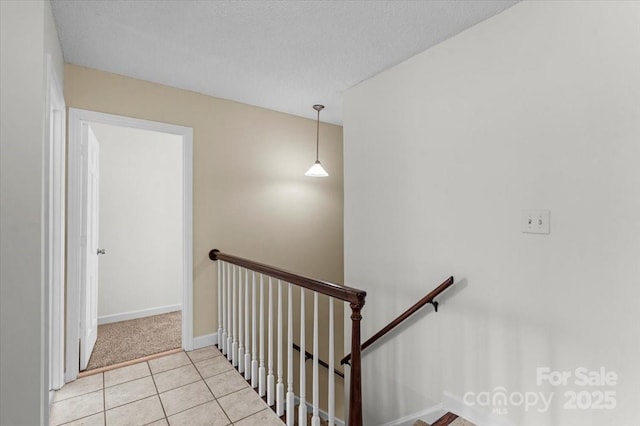 stairway featuring tile patterned floors and a textured ceiling