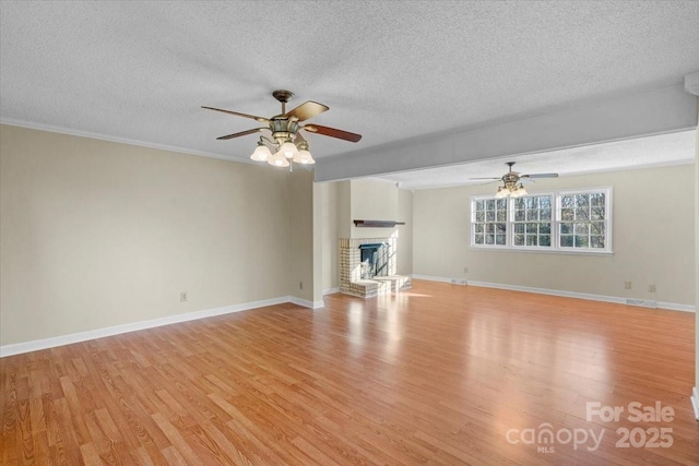 unfurnished living room with ceiling fan, a fireplace, a textured ceiling, and light wood-type flooring