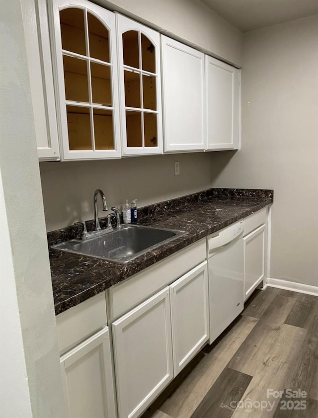 kitchen with sink, hardwood / wood-style flooring, white cabinetry, white dishwasher, and dark stone counters