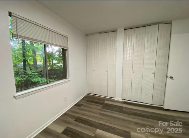 unfurnished bedroom with dark wood-type flooring and two closets