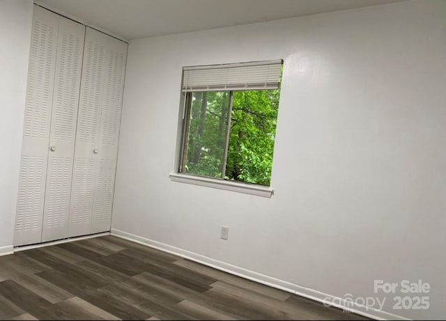 unfurnished bedroom with dark wood-type flooring and a closet