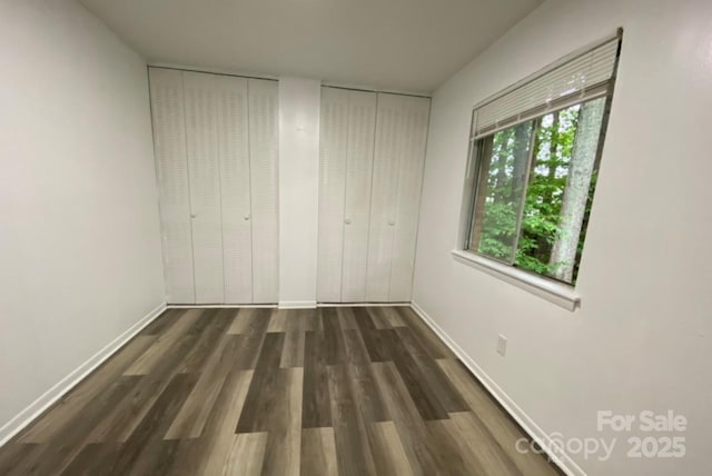 unfurnished bedroom with multiple closets and dark hardwood / wood-style flooring