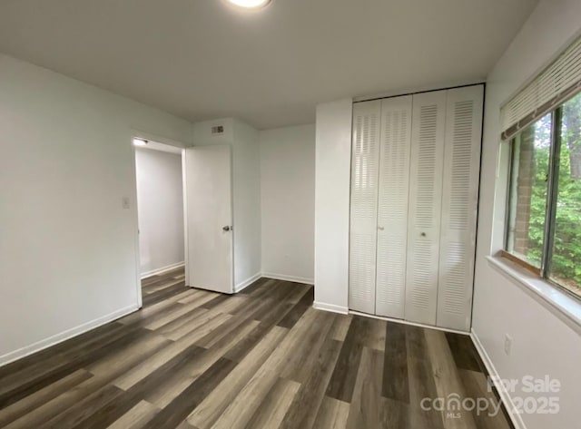 unfurnished bedroom featuring dark hardwood / wood-style flooring and a closet