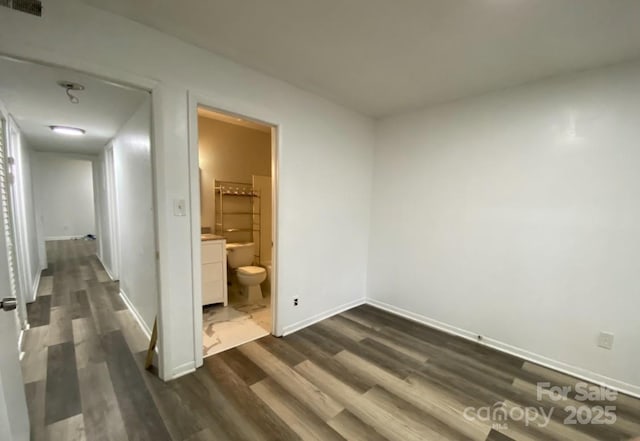 unfurnished bedroom featuring dark wood-type flooring and ensuite bathroom