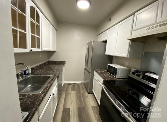 kitchen with sink, hardwood / wood-style floors, stainless steel appliances, white cabinets, and dark stone counters